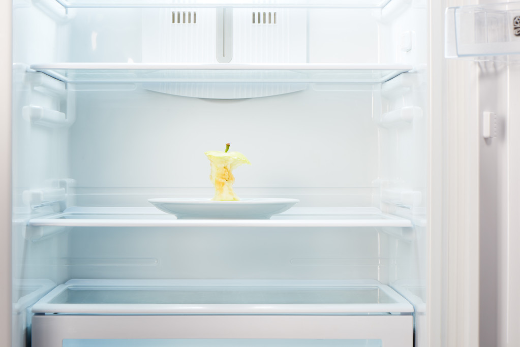 Núcleo de maçã na placa branca no refrigerador vazio aberto
 - Foto, Imagem