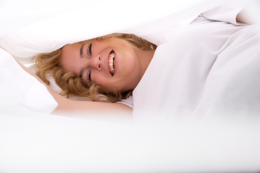 Nuori nainen piilossa sängyssä alla lakanat
 - Valokuva, kuva