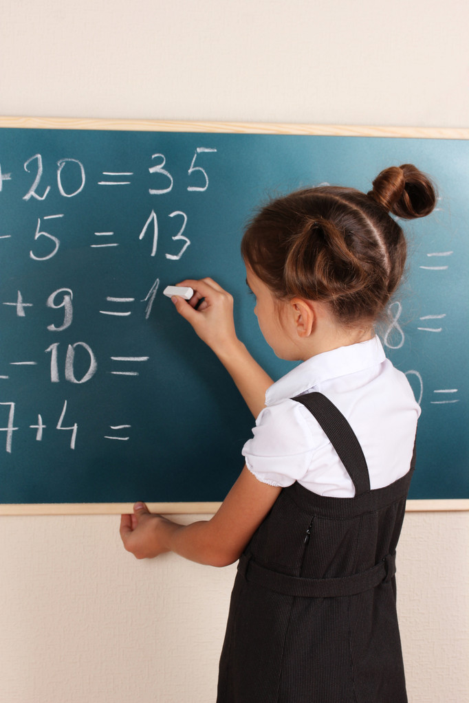 Beautiful little girl writing on classroom board - Photo, Image