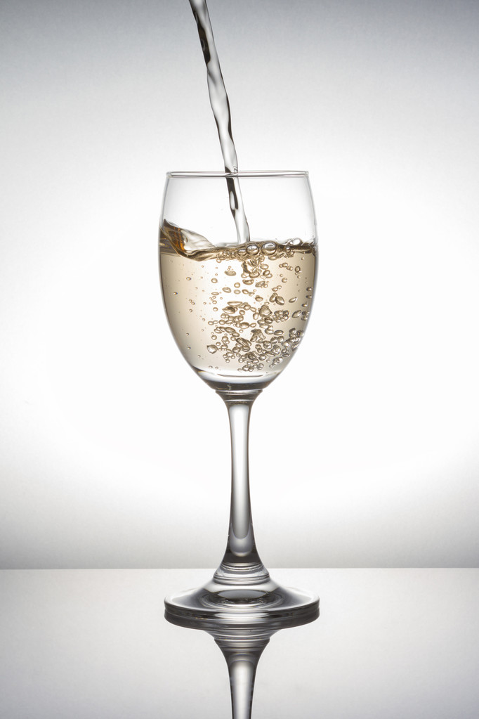 White wine pouring into wineglass on white background - Photo, Image