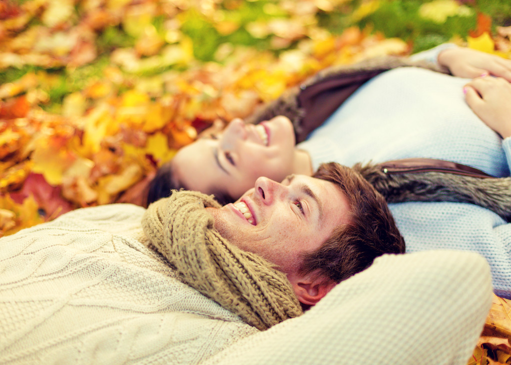 Close up van lachende paar liggen in de herfst park - Foto, afbeelding