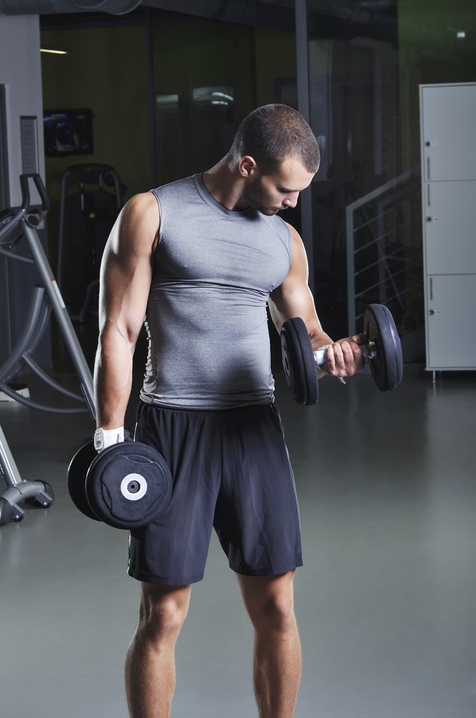 Jóképű, izmos férfi-modellt a súlyzók bicepsz feladatot álló helyzetben - Fotó, kép