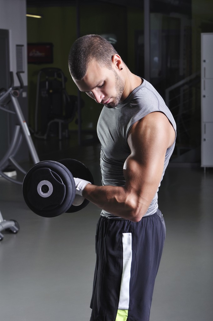 Красивый мускулистый мужчина модель делает бицепсы упражнения с гантелями
 - Фото, изображение