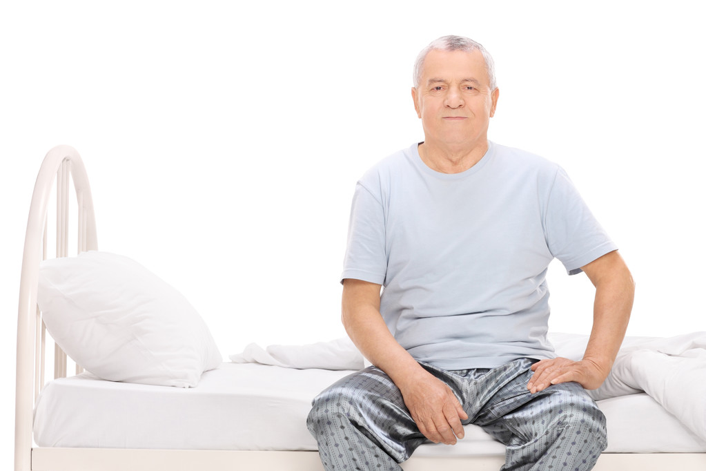 Senior man in pajamas sitting on a bed - Photo, Image