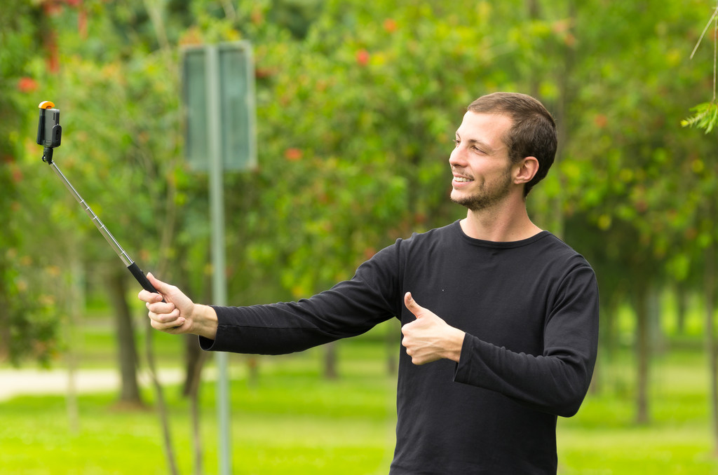 Uomo ispanico in posa con bastone selfie in ambiente parco sorridente
 - Foto, immagini