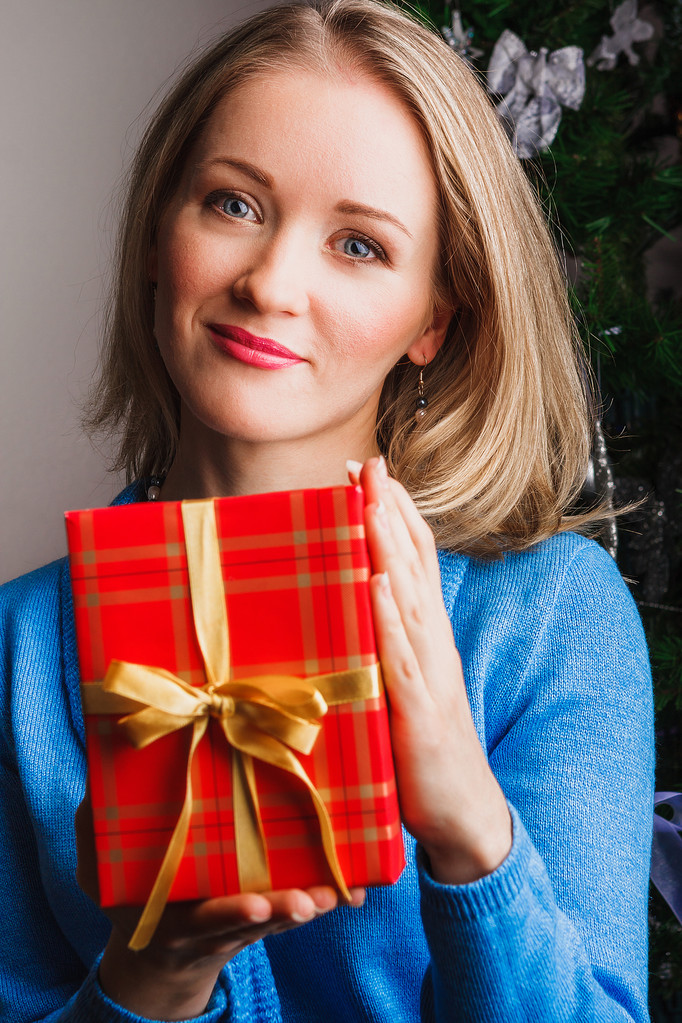 Lovely woman in blue sweater keeps red gift - Photo, Image
