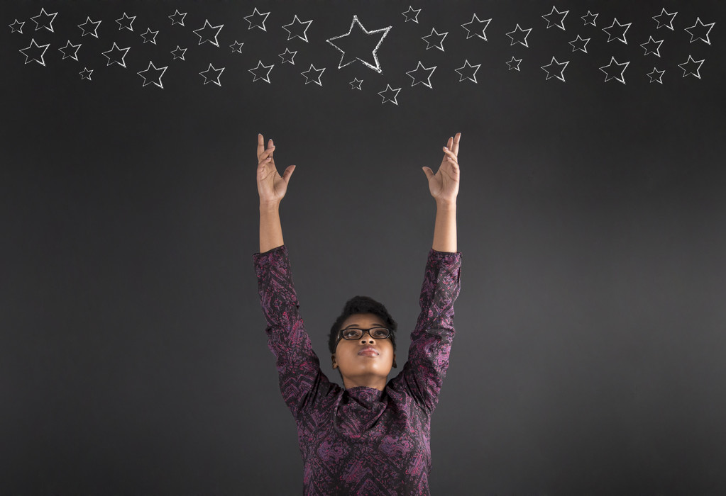 African American woman teacher or student reaching for the stars on blackboard background - Zdjęcie, obraz