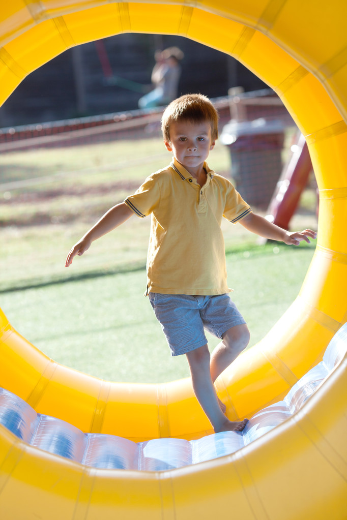 Симпатичный маленький мальчик, играет в катящемся пластиковом кольце цилиндра, полный
 - Фото, изображение
