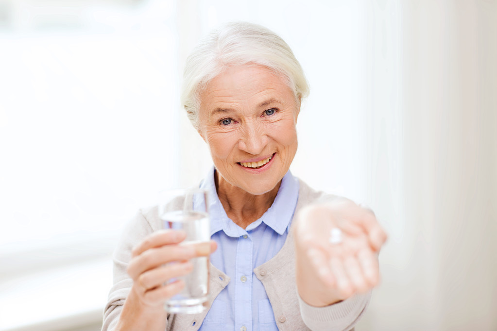mulher sênior feliz com água e medicina em casa
 - Foto, Imagem