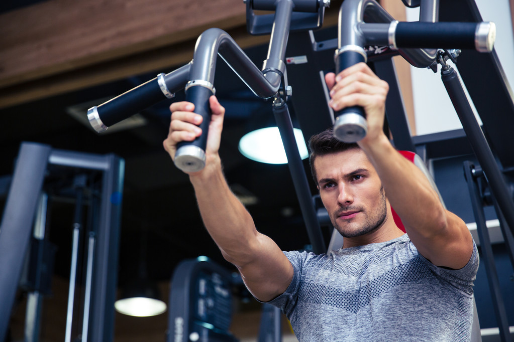 Spor salonunda fitness makinede egzersiz yaparak vücut geliştirmeci - Fotoğraf, Görsel