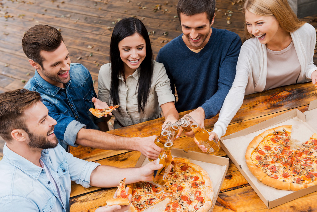 people clinking bottles and eating pizza - Photo, Image