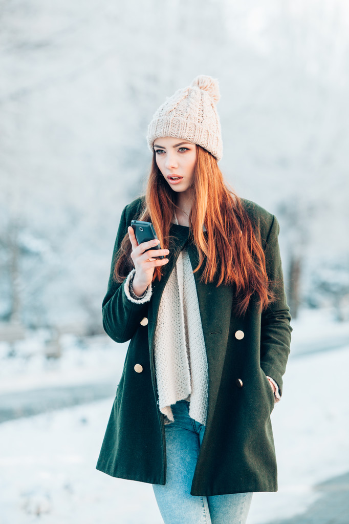 Akıllı telefon ve kış manzarası ile gülümseyen genç kadın . - Fotoğraf, Görsel