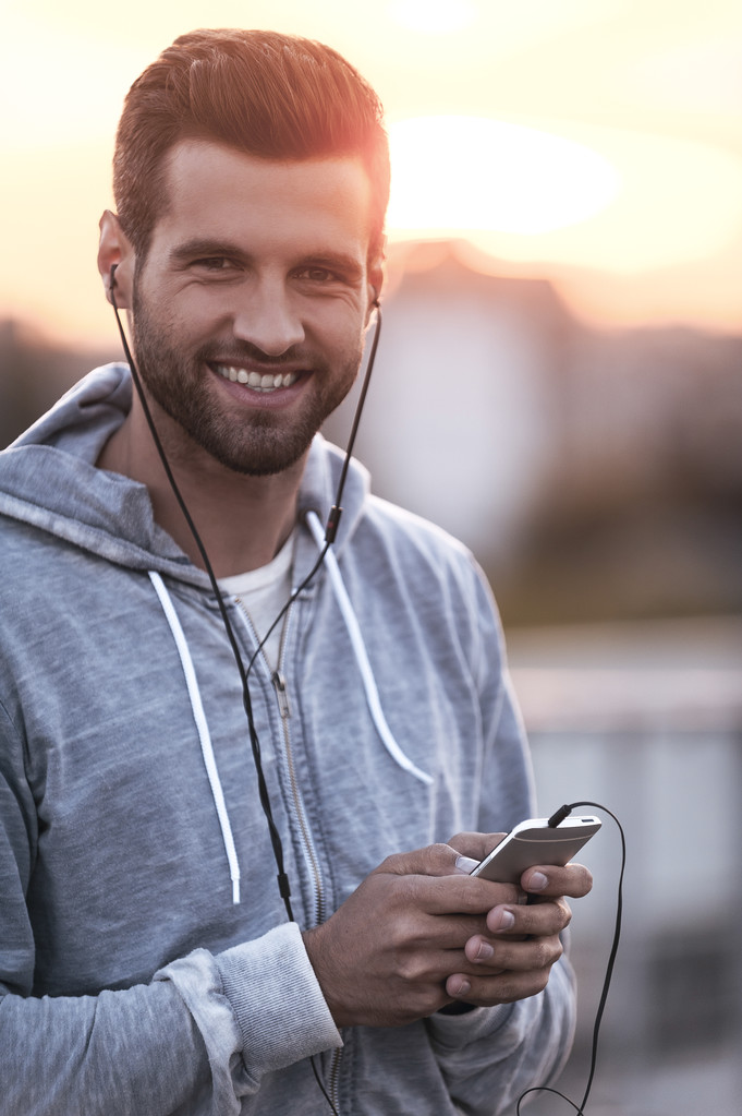 Hombre con auriculares sosteniendo el teléfono móvil
 - Foto, imagen