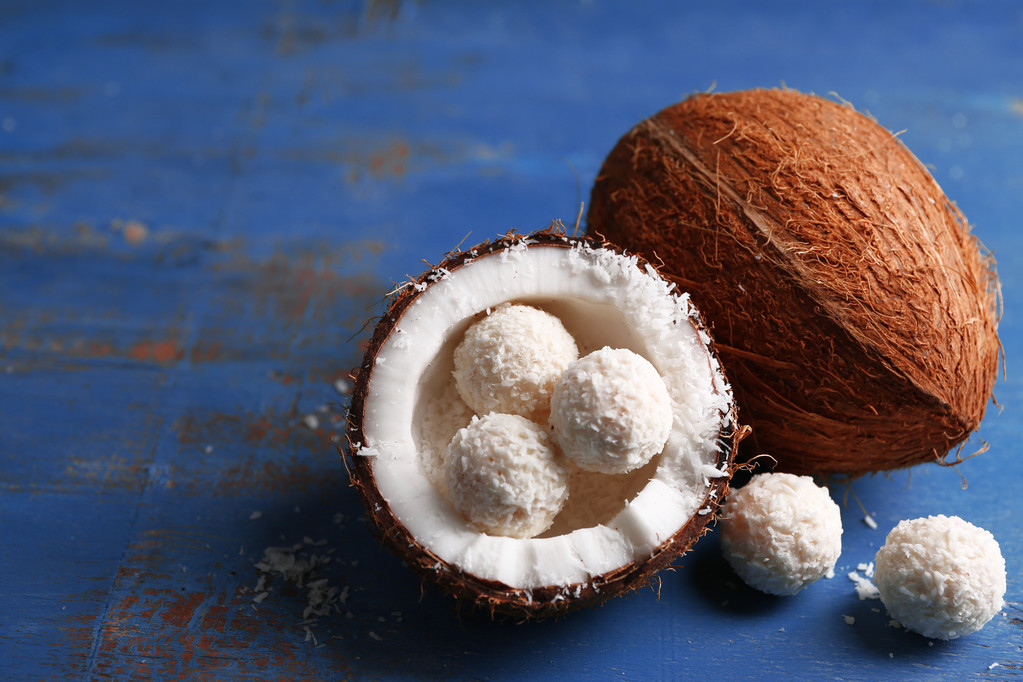 Bonbons en flocons de noix de coco et noix de coco fraîche sur fond de bois de couleur
 - Photo, image