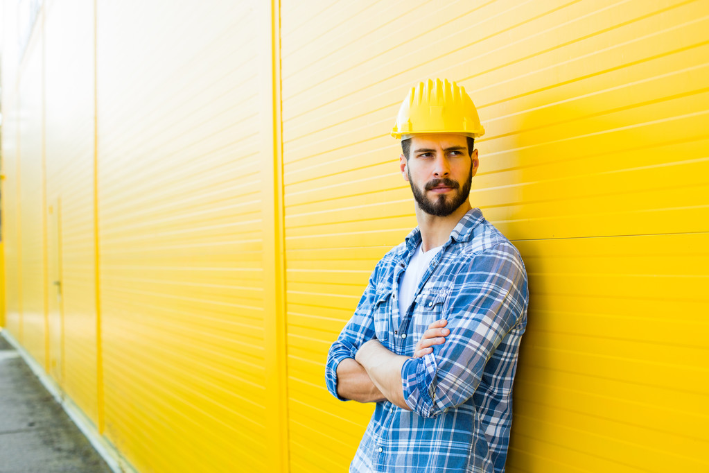 взрослый работник со шлемом на желтой стене
 - Фото, изображение