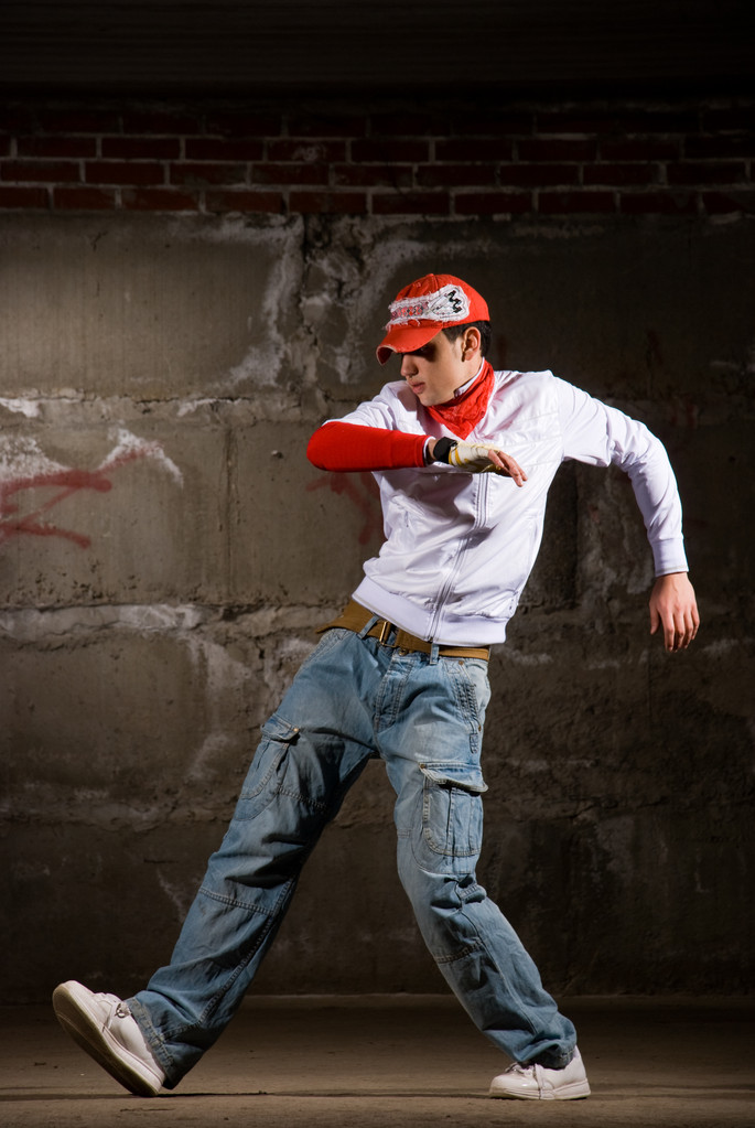 chłopiec hip-hopowy taniec w nowoczesnym stylu ponad szary mur - Zdjęcie, obraz
