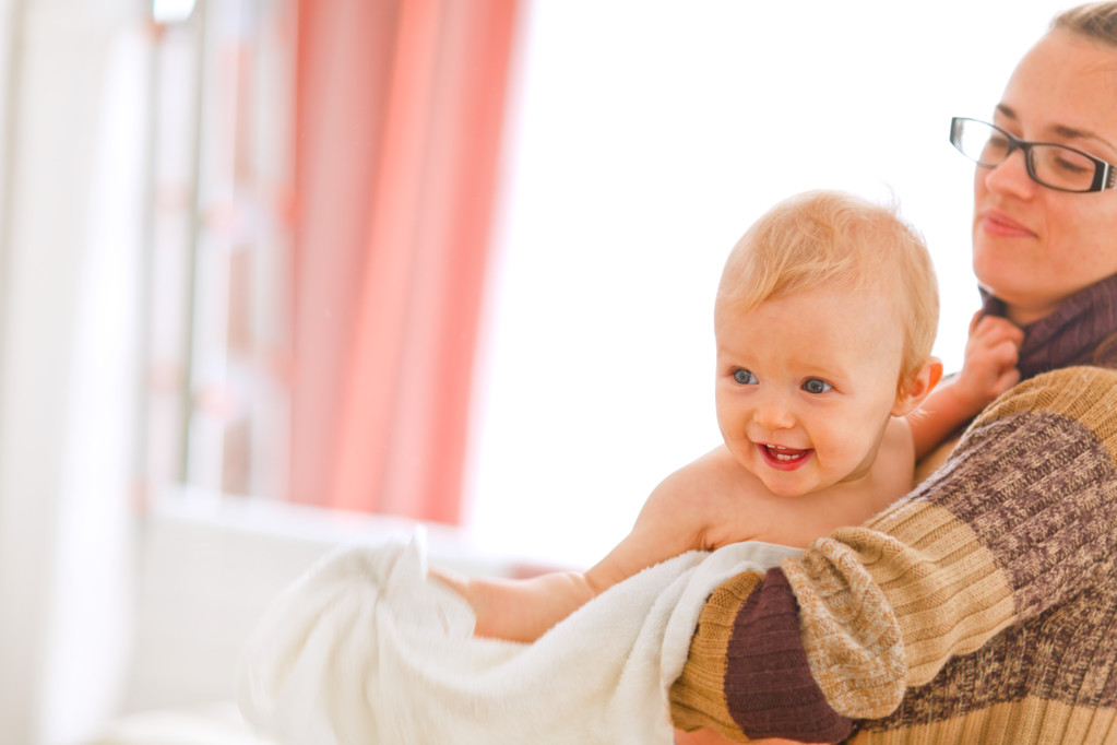Веселый ребенок на руках у мамочек, смотрящий в угол
 - Фото, изображение