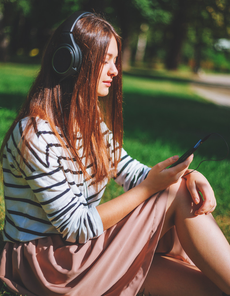 Jong meisje luisteren naar muziek in park - Foto, afbeelding