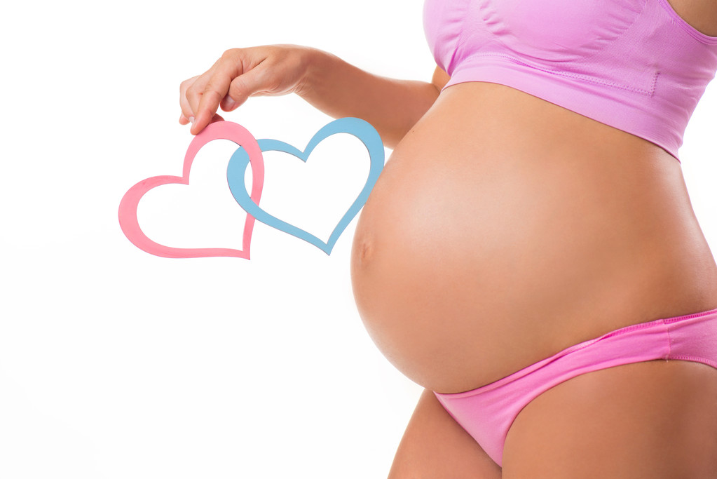 Close-up of a pregnant belly with pink and blue hearts. Guess the sex of the baby-child: girl, boy or twins. - Photo, Image