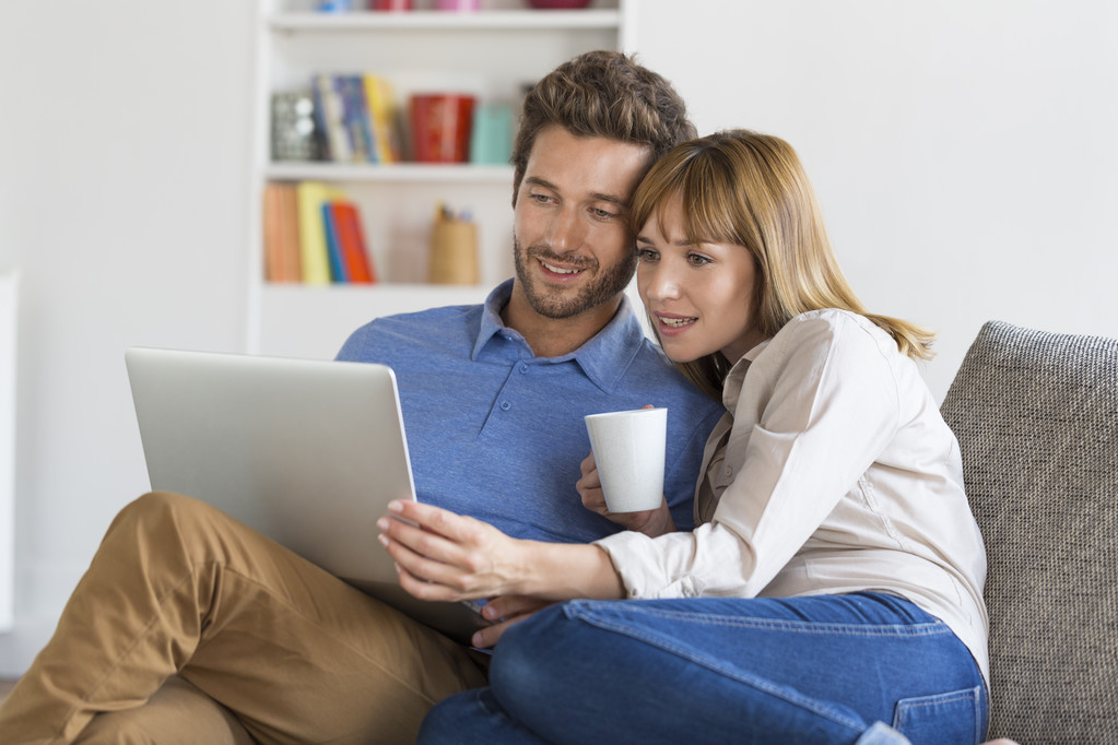 pareja joven usando el ordenador portátil en el sofá en casa - Foto, Imagen