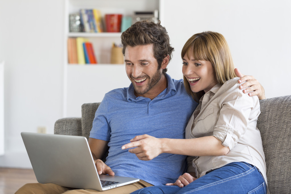 Young couple surfing on internet with laptop on sofa at home - Photo, Image