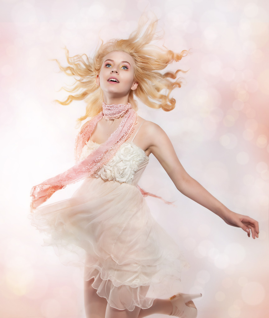 mooie artistieke jong meisje blonde haren vliegen over roze achtergrond - Foto, afbeelding