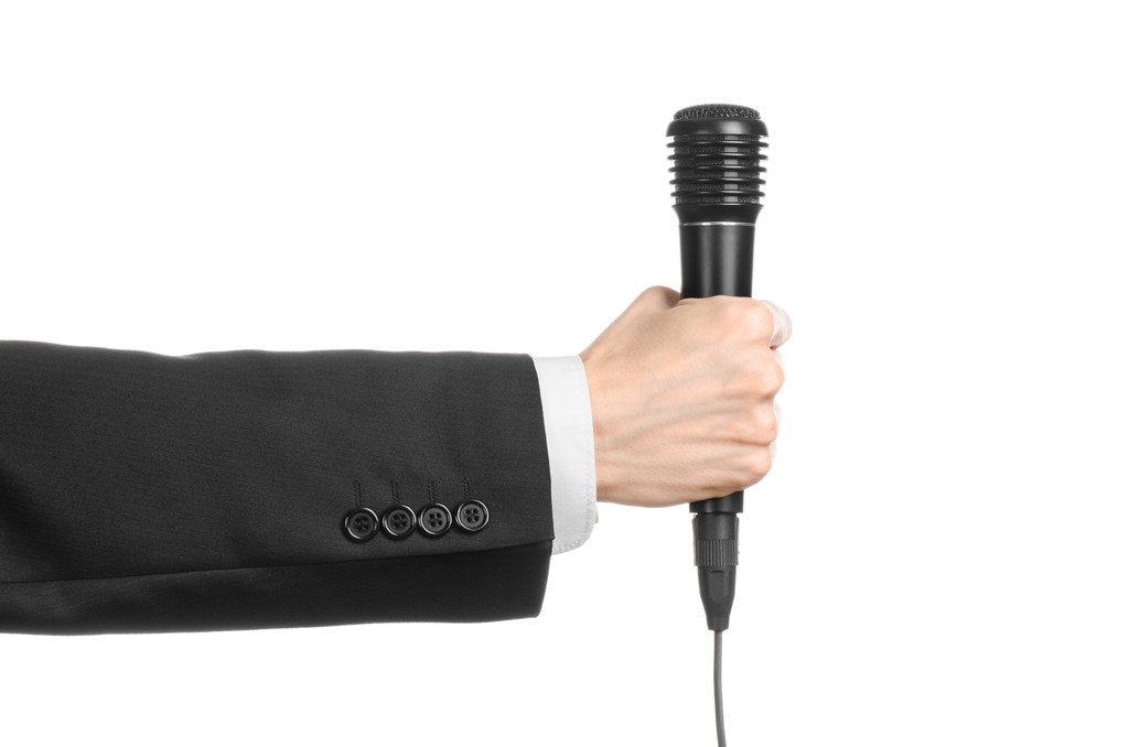 Тема бізнесу та мови: Чоловік у чорному костюмі тримає чорний мікрофон ізольовано на білому тлі в студії
 - Фото, зображення