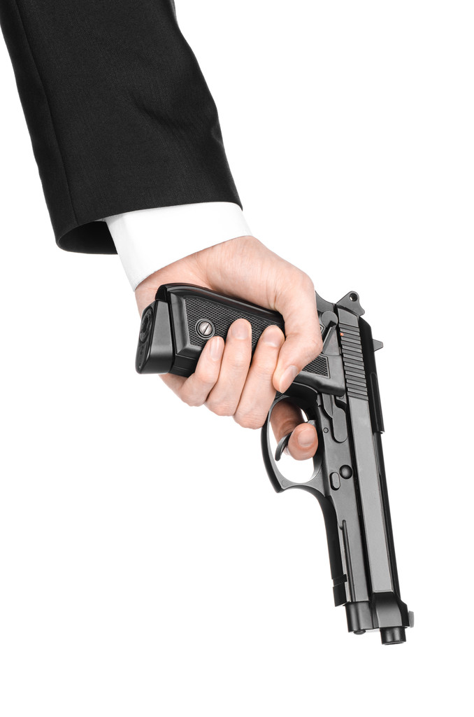 Armi da fuoco e sicurezza argomento: un uomo in giacca e cravatta nera che tiene una pistola su uno sfondo bianco isolato in studio
 - Foto, immagini