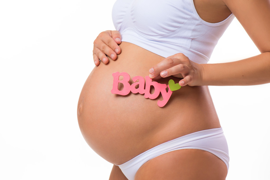 Zwangere buik met roze inscriptie voor babymeisje. Zwangere vrouw te wachten een dochter. Close-up horizontaal geïsoleerd op witte achtergrond. - Foto, afbeelding