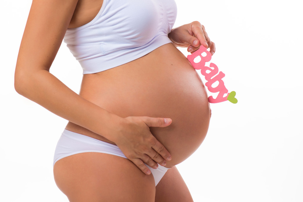 Vientre embarazada con inscripción rosa para niña. Mujer embarazada esperando a una hija. Primer plano horizontal aislado sobre fondo blanco
. - Foto, Imagen