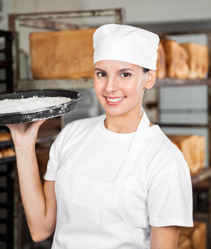 Femme boulanger souriant tout en portant plateau de pâte
 - Photo, image
