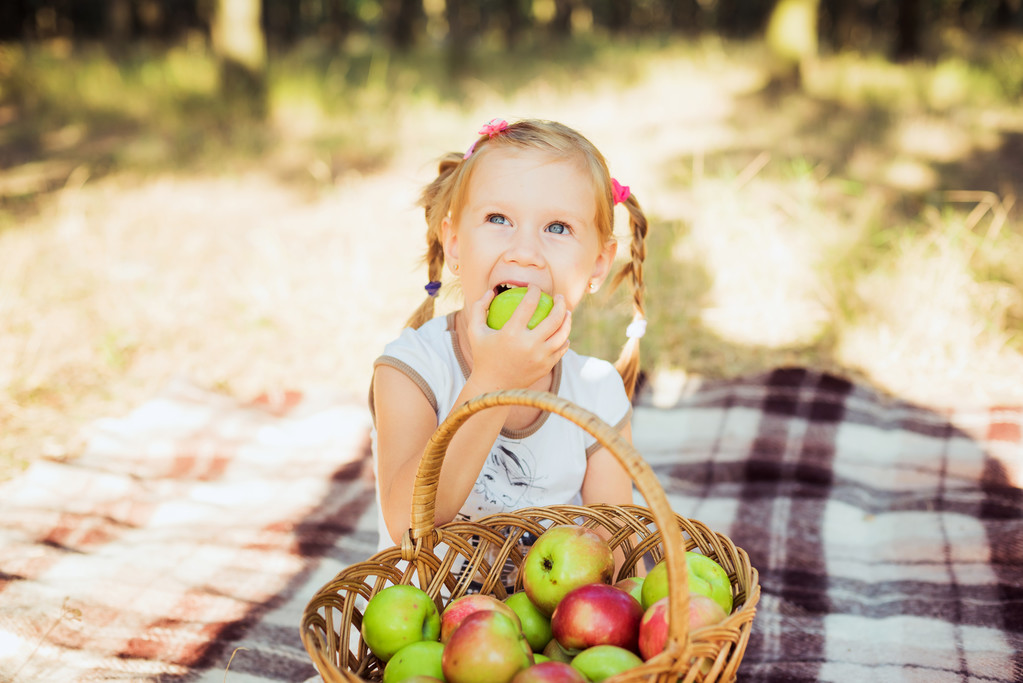 маленька дівчинка з яблуками в парку
 - Фото, зображення