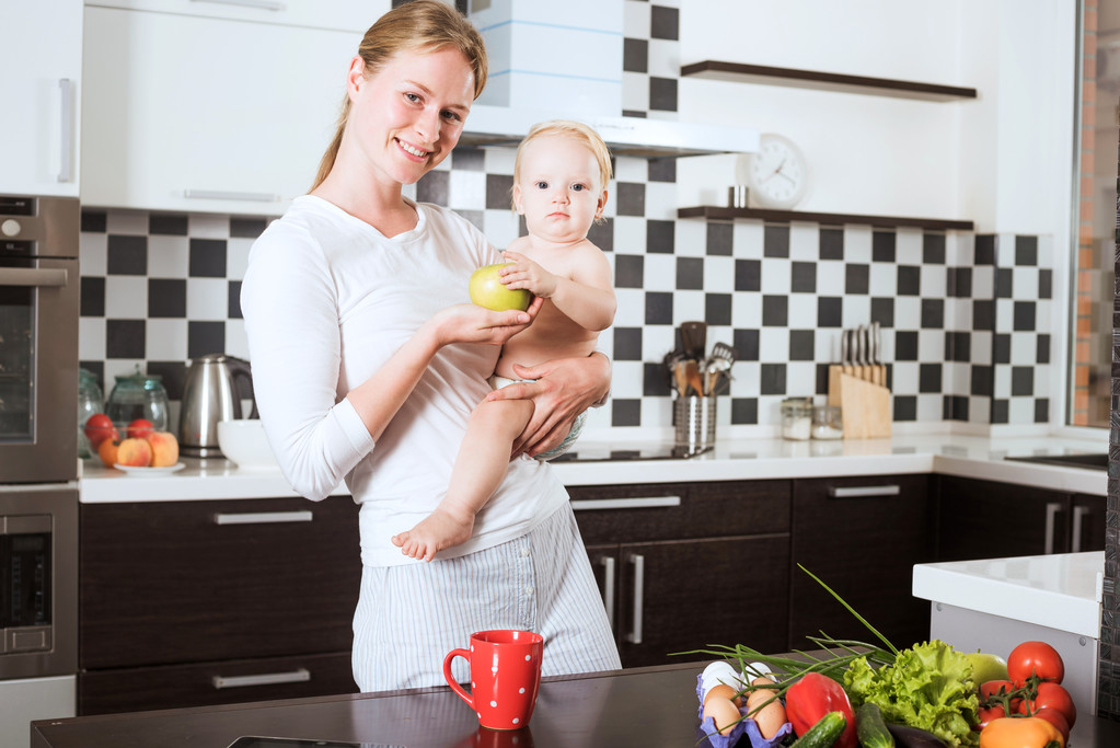 Matka drží dcera v kuchyni při vaření jídlo z čerstvé zeleniny a ovoce. Matka a malou dceru na kuchyň, ale napřed. Zdravé výživy a zdravého života koncepce - Fotografie, Obrázek