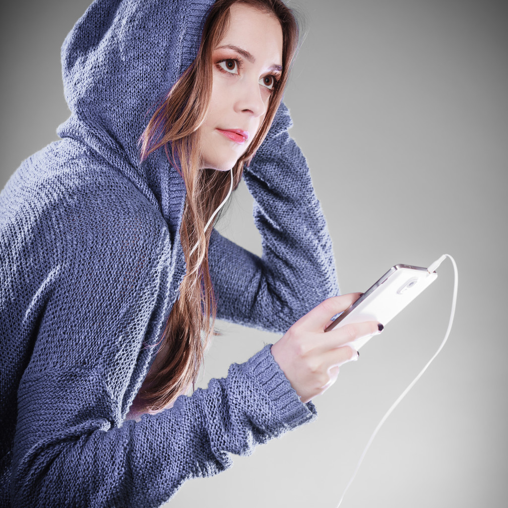 スマートフォンで音楽を聴いている若い女性は - 写真・画像