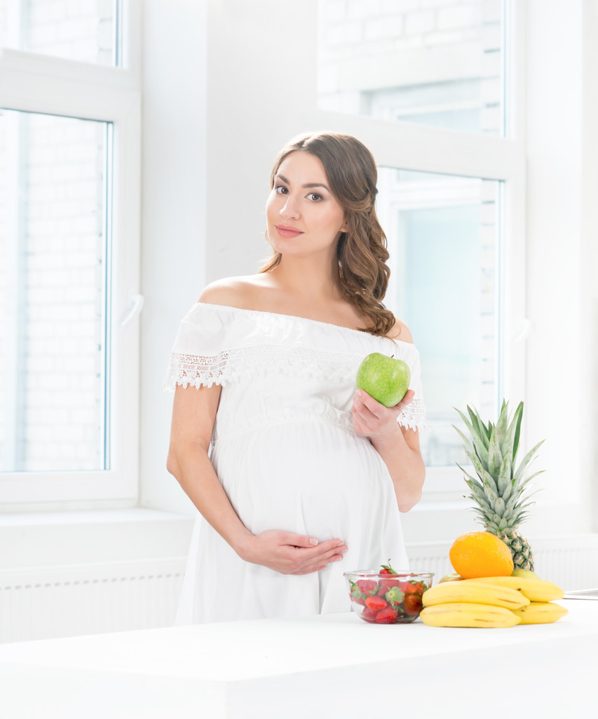 kobieta w ciąży w kuchni jedzenie owoców - Zdjęcie, obraz