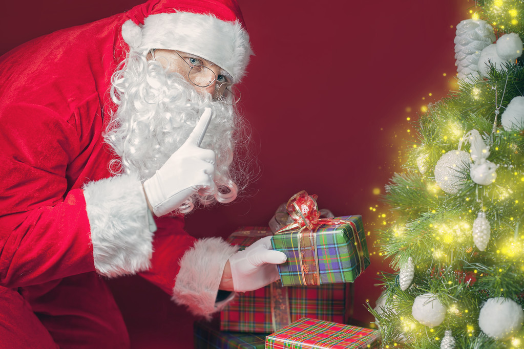 Санта Клаус кладет подарочную коробку или подарок под елку
 - Фото, изображение