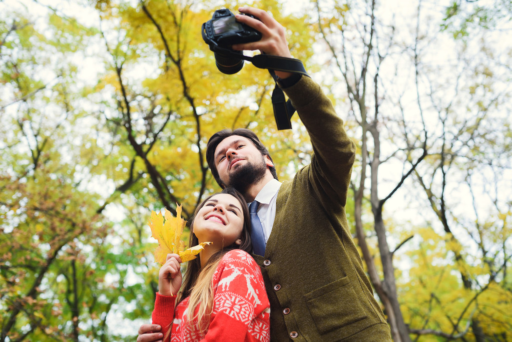 jonge gelukkige paar maken selfie camera met najaar park - Foto, afbeelding