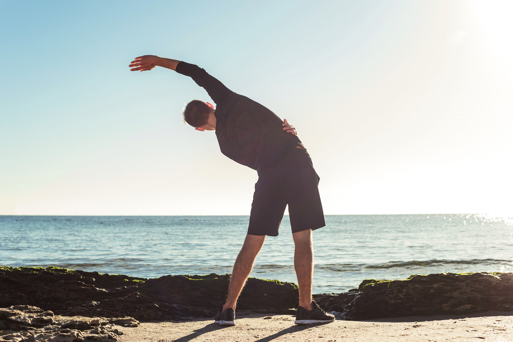 junger Mann trainiert am Strand, sportlicher Mann macht Übungen - Foto, Bild