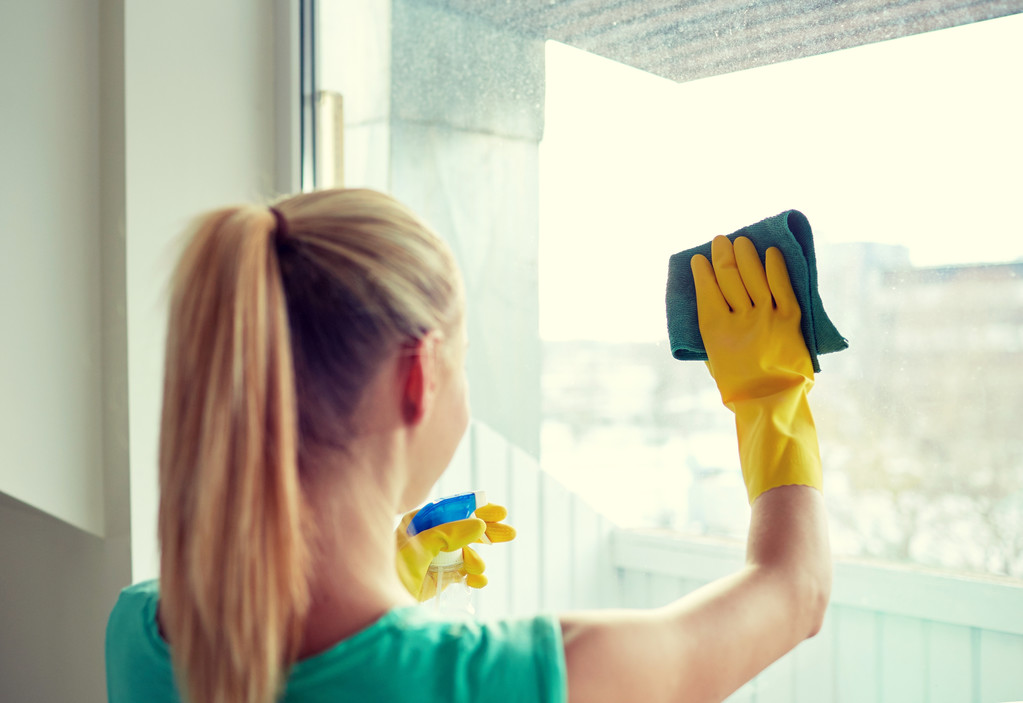 glückliche Frau in Handschuhen, die Fenster mit Lappen putzt - Foto, Bild