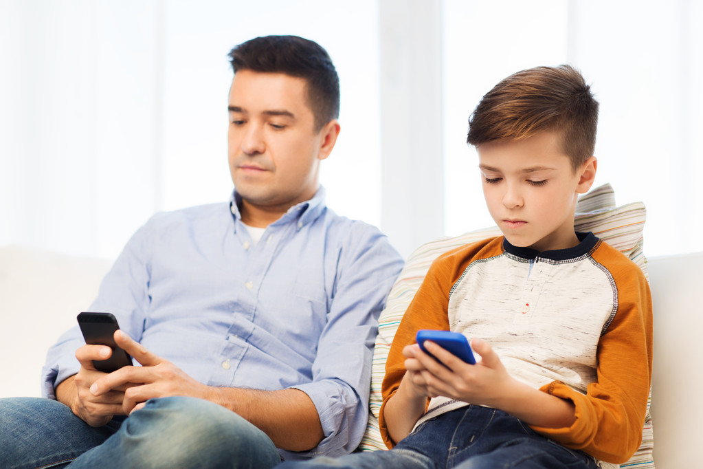 vader en zoon met smartphones thuis - Foto, afbeelding