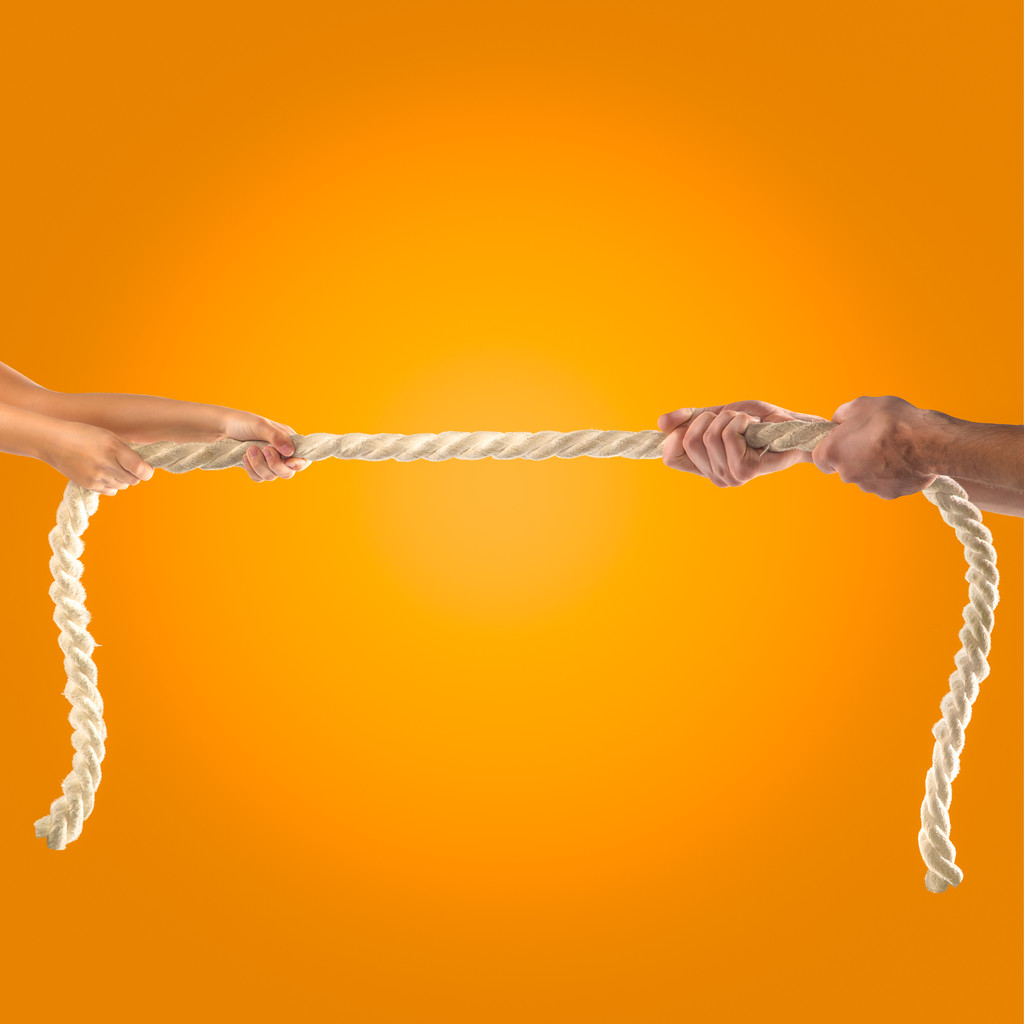 Lányok kezében és felnőtt férfiak húz a kötelet, a narancssárga háttérrel. Verseny fogalma - Fotó, kép