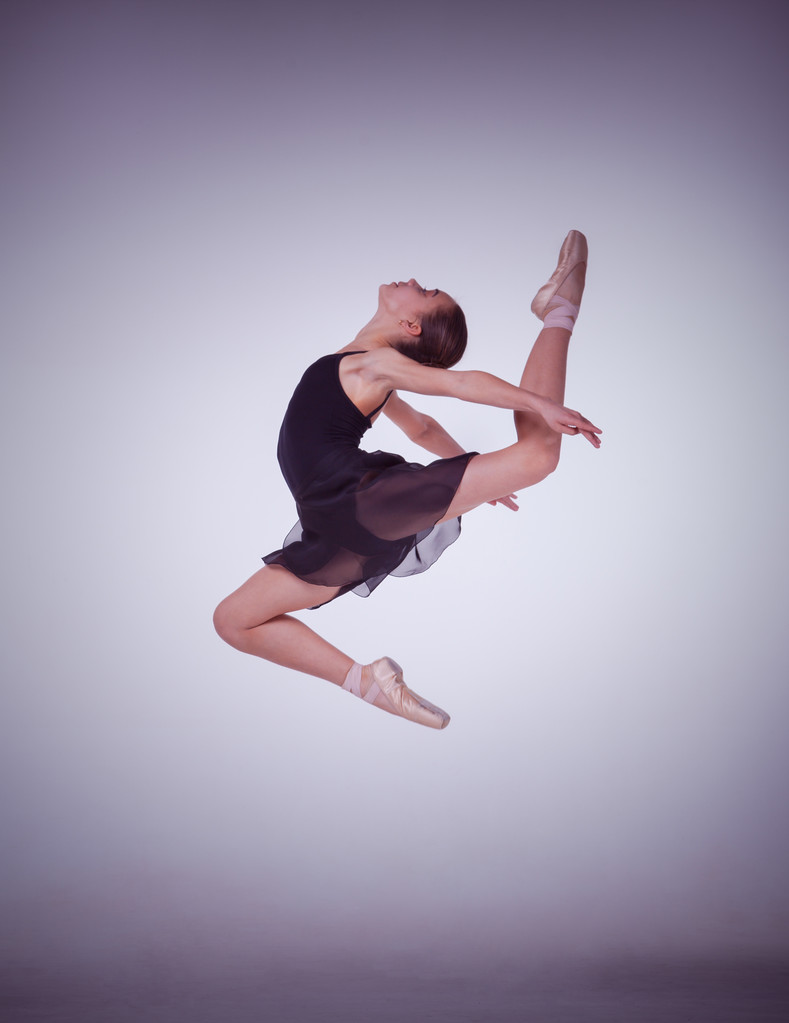 die Silhouette einer jungen Balletttänzerin, die auf fliederfarbenem Hintergrund springt. - Foto, Bild