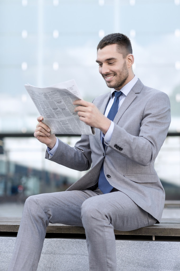 jonge lachende zakenman krant buitenshuis - Foto, afbeelding