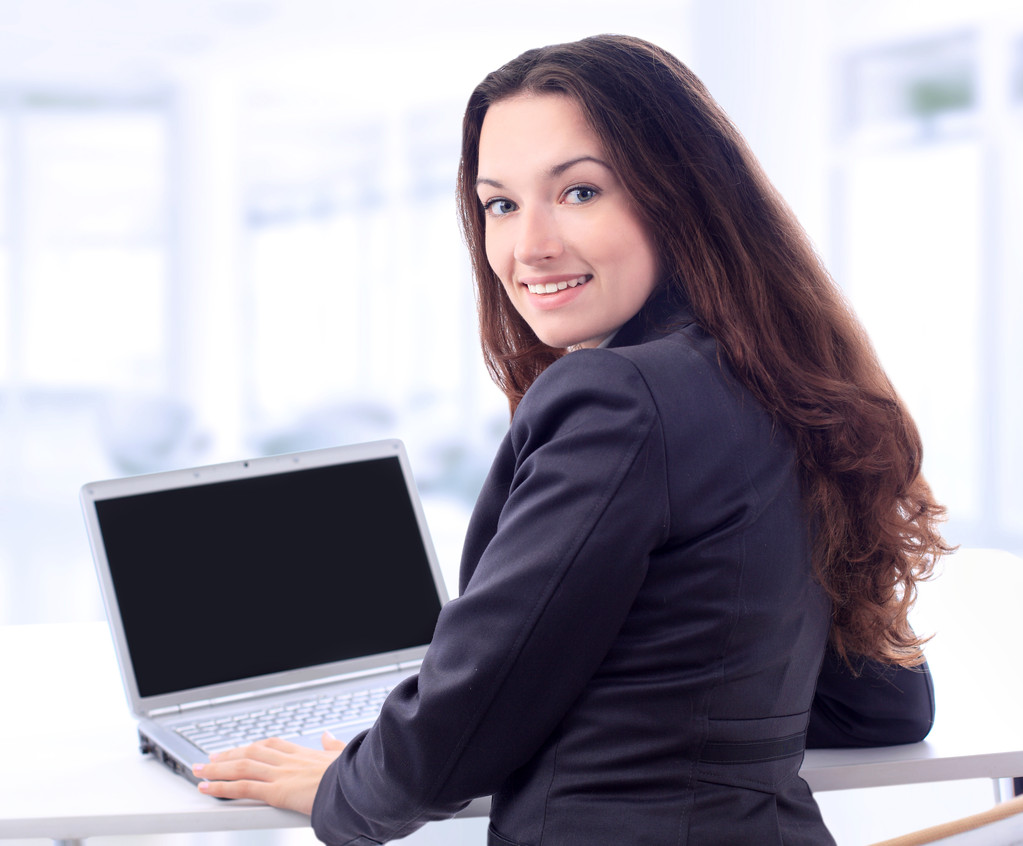 Femme d'affaires réfléchie pour un ordinateur portable dans le bureau avec un sourire
. - Photo, image