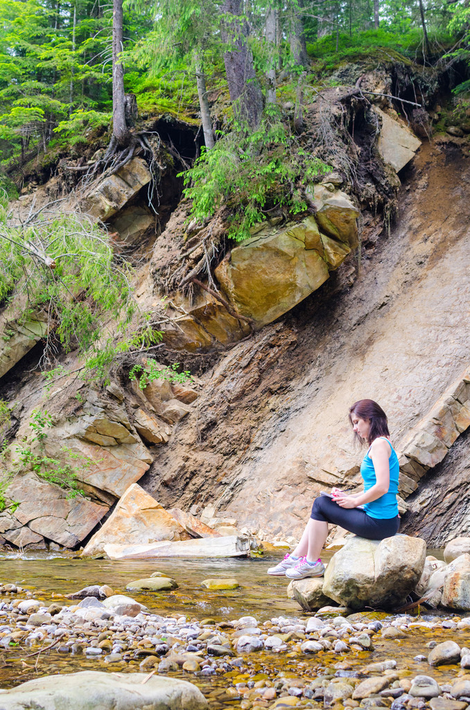 schöne junge Mädchen sitzt auf einem Felsen im Fluss und schöpft aus - Foto, Bild