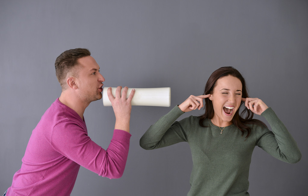 Hombre hablando a través de tubo y una mujer tapándose las orejas
 - Foto, Imagen