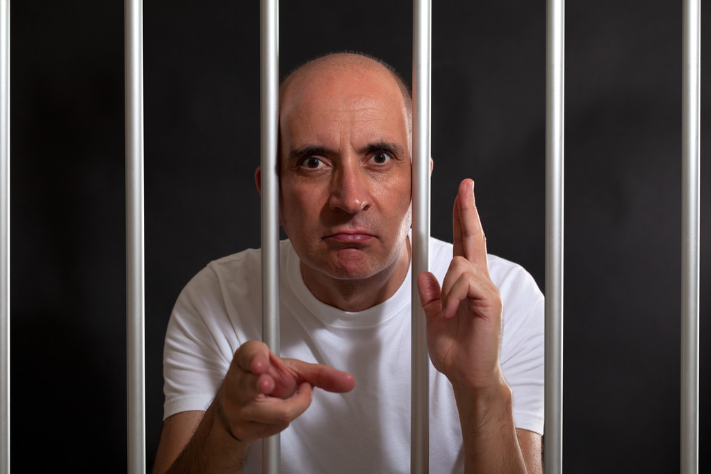 Чоловік у в'язниці жестикулює зброєю своїми руками
 - Фото, зображення