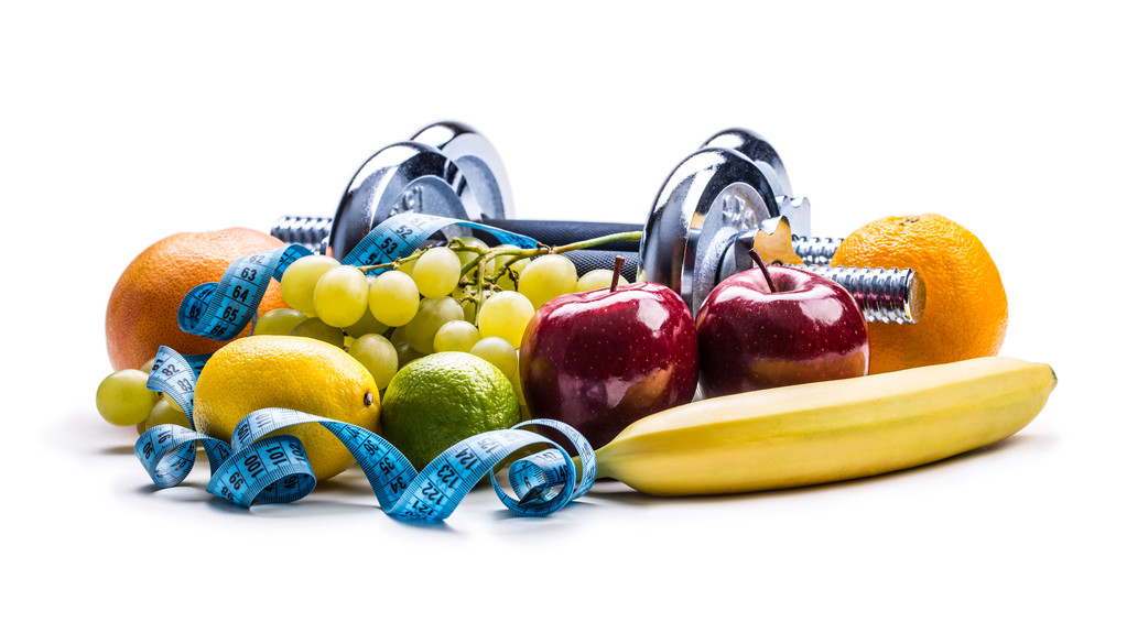 halteres cercado com frutas saudáveis fita métrica em um fundo branco com sombras
. - Foto, Imagem
