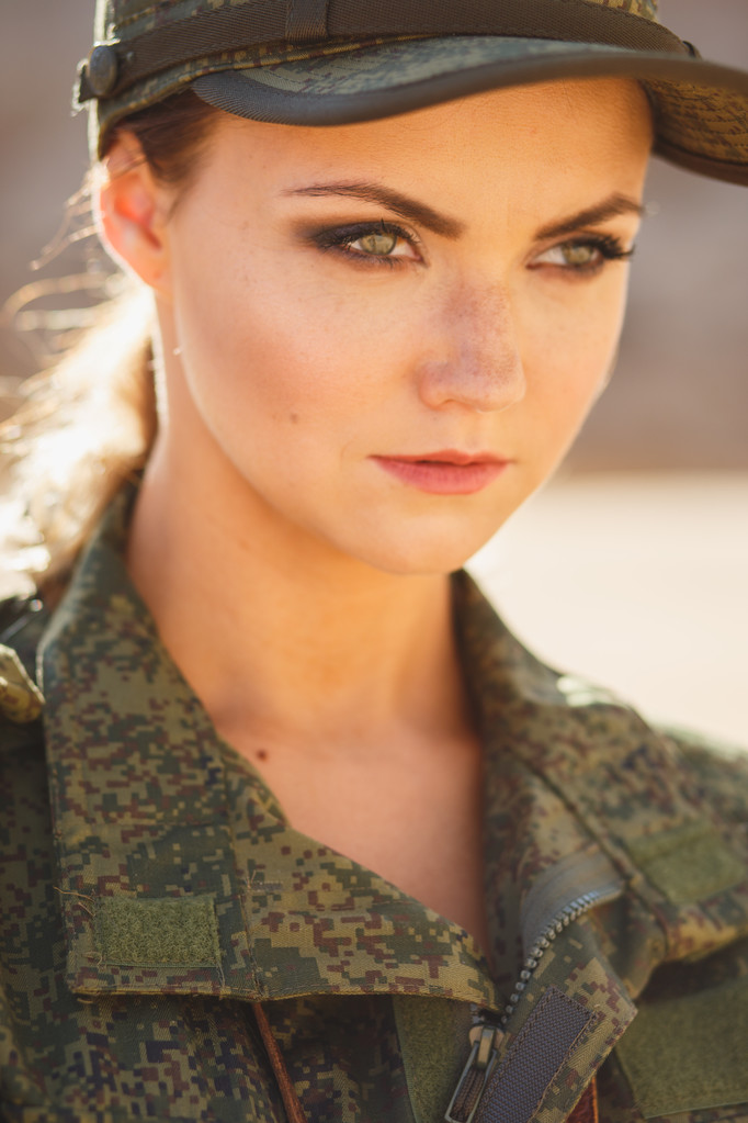 Linda jovem mulher em um traje militar no fundo de uma sobremesa
 - Foto, Imagem
