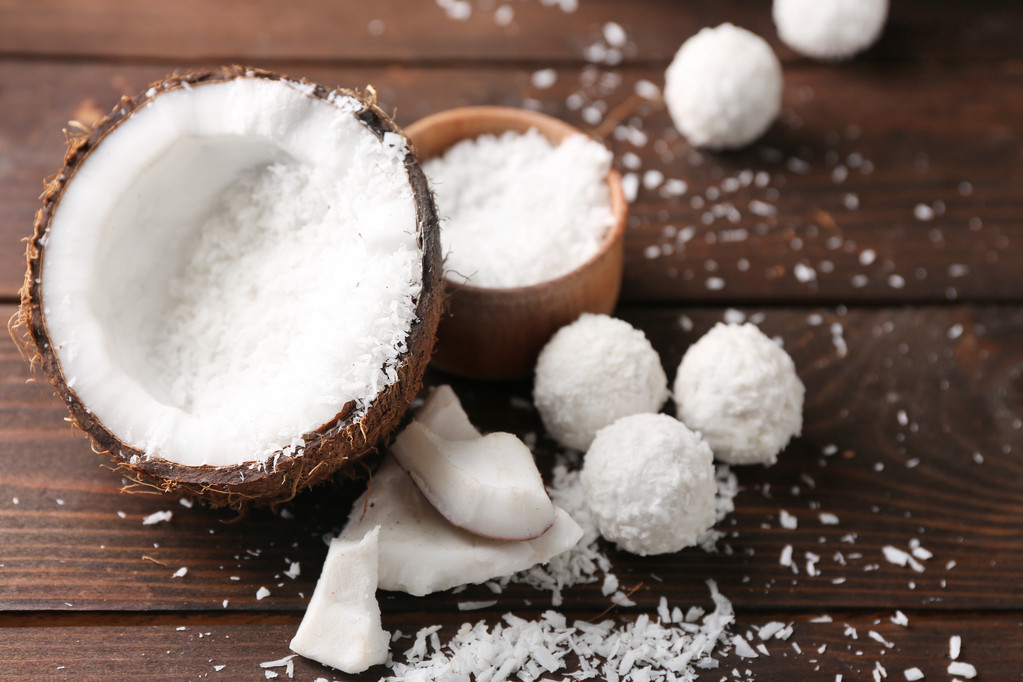 Candies in coconut flakes, glass of milk and fresh coconut on dark wooden background - Photo, Image